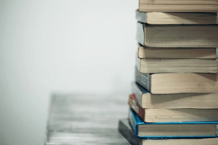 A pile of assorted books on a wooden table