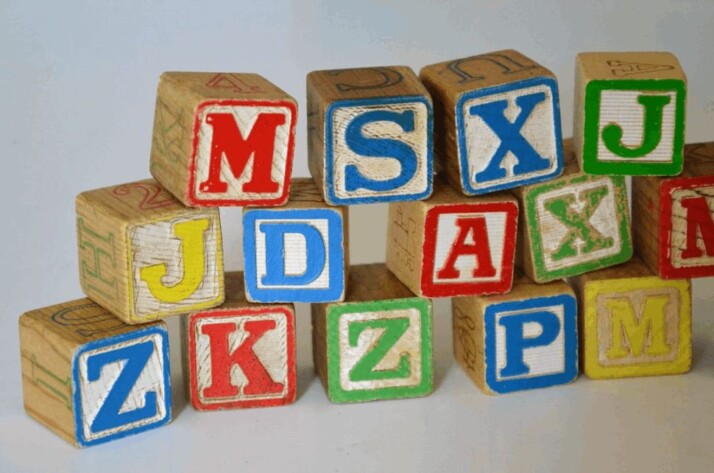 Multicolored wooden letter blocks toy stacked on the ground.