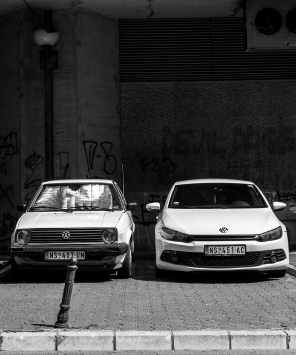 grayscale photo of two Volkswagen cars parked on sidewalk