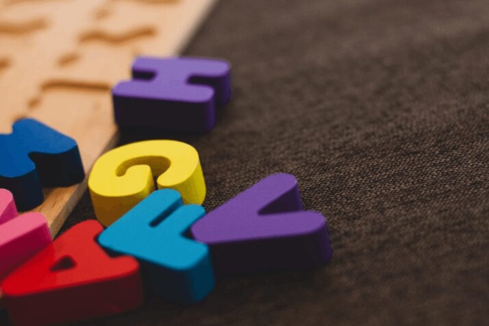 Multi-colored alphabet learning toy placed on a brown apparel.