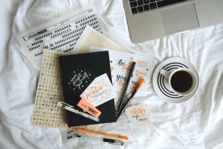 white ceramic mug on white ceramic saucer with books and pens