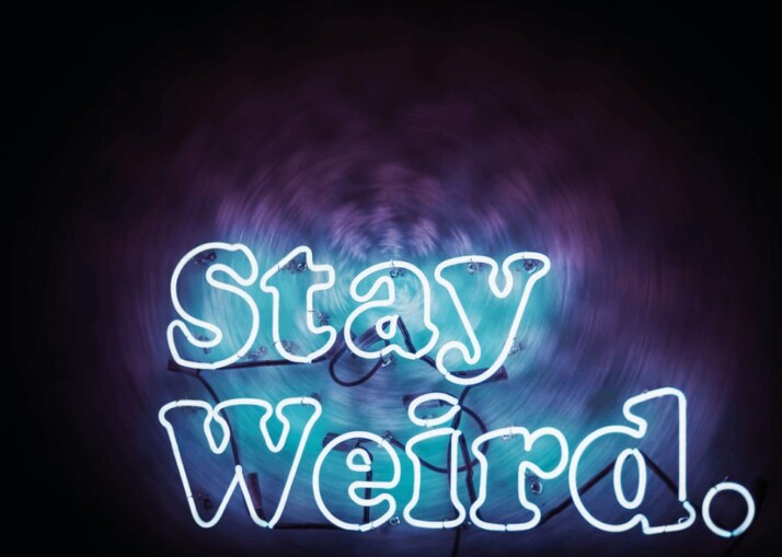 Stay Weird text in blue over a black background. 