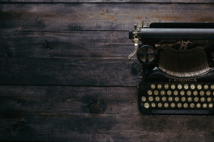 a black Corona typewriter with qwerty keyboard on brown wood planks