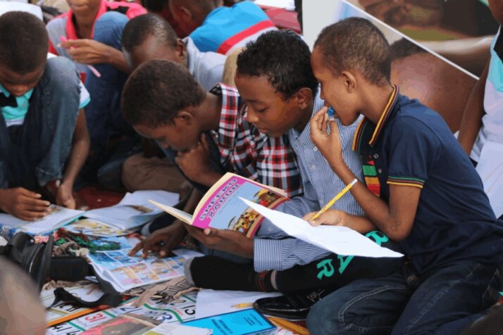 boy in blue and white plaid shirt reading book