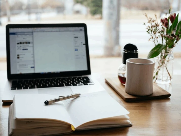 MacBook Pro near white open book and a cup of coffee 