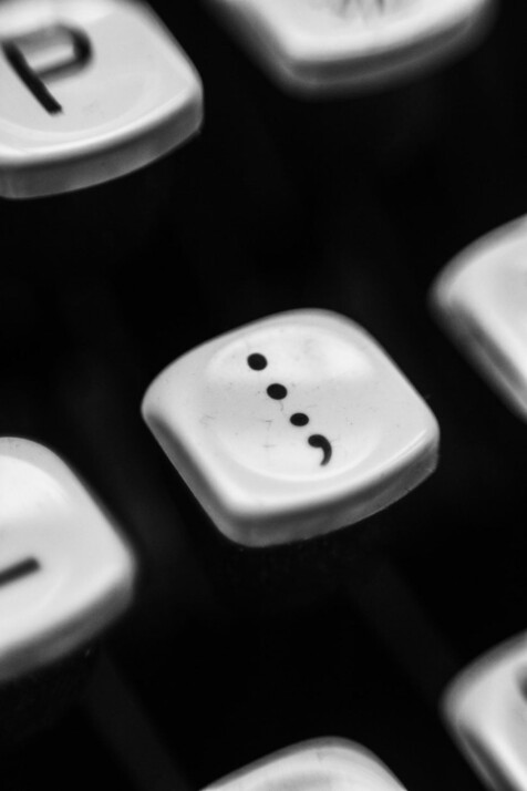 gray typewriter showing colon and semi-colon key with other letters