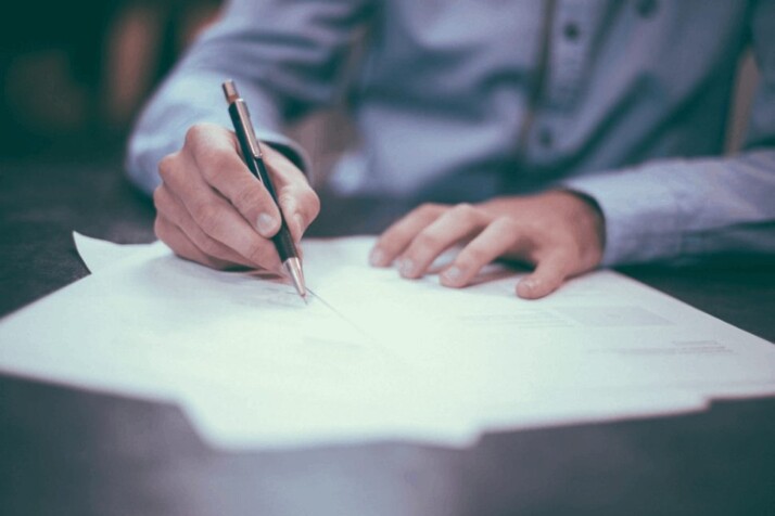 A man in blue shirt writing on a paper