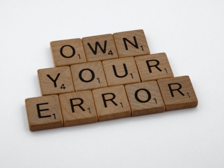 Own Your Errors brown wooden scrabble blocks on a white surface