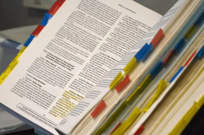 An open white book with multicolored sticky note labels. 