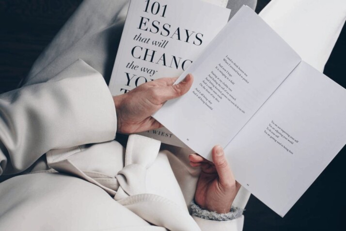 A person wearing a white coat is holding a book