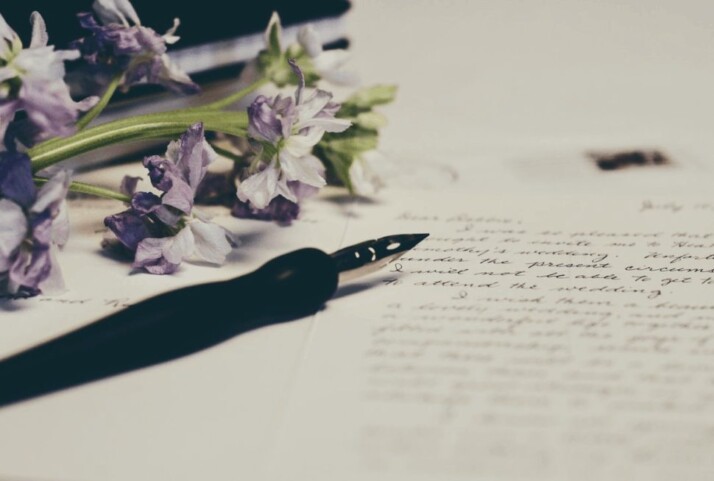 Sticks of purple flowers and a pen on paper