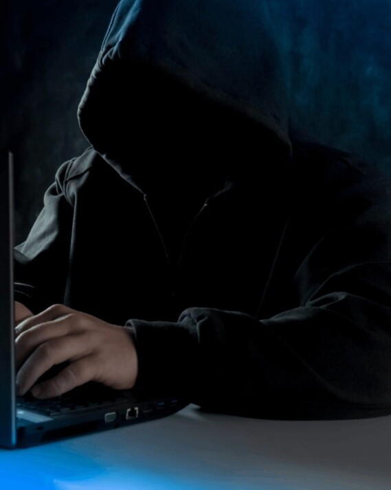 person in black hoodie using laptop computer on white surface