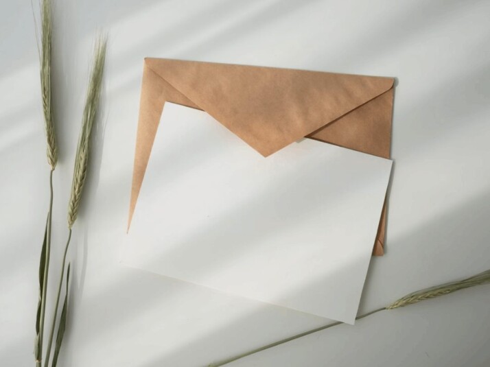 white paper and brown envelope on white surface with light reflection
