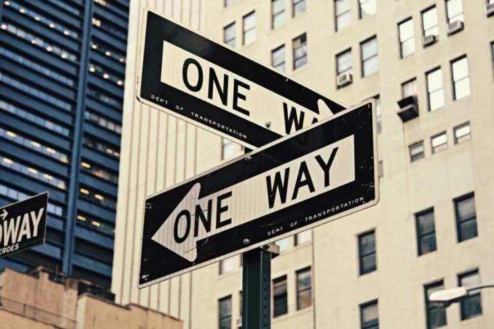 Two white and black One Way-printed road signages placed perpendicularly