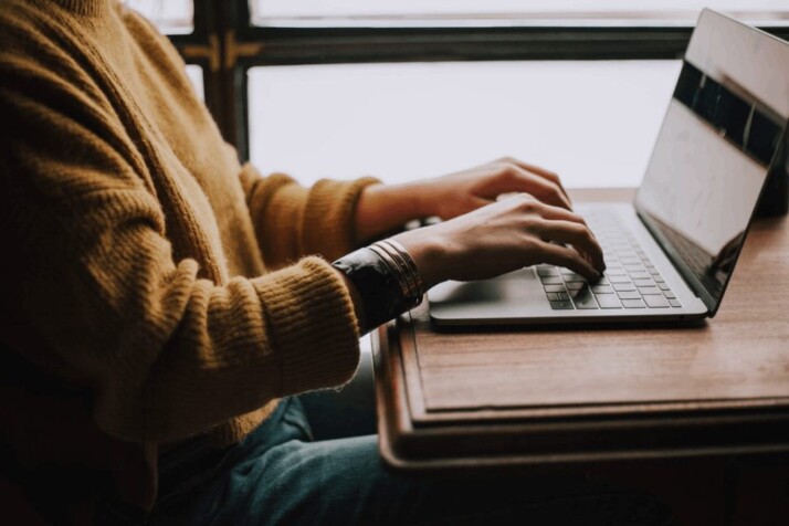 A person sitting in front of a laptop and typing