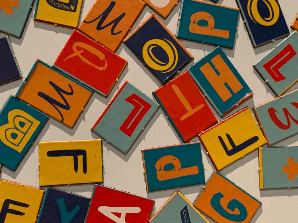 Multicolored letter blocks are scattered on a white surface.