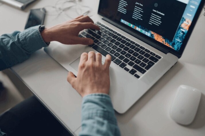 person wearing long-sleeve top working on a silver laptop