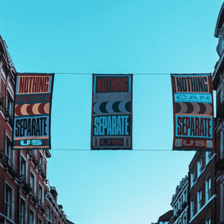 photo of three signs between apartment blocks that reads nothing can separate us