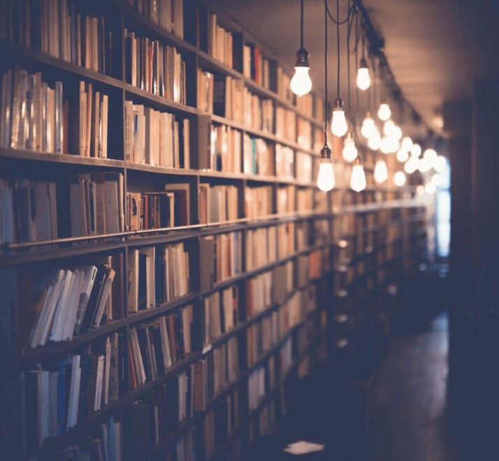 photo of a library with hanging lights that are turned on.