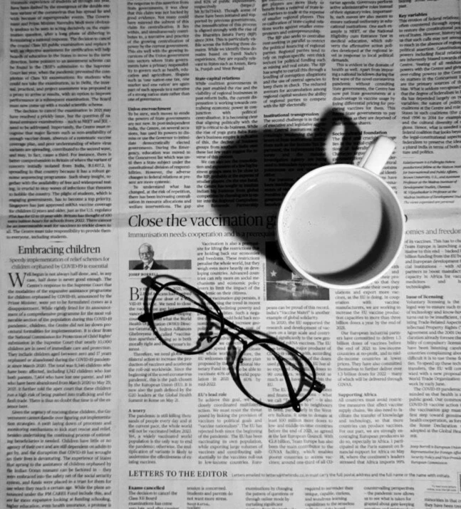 Black eyeglasses on a big newspaper with a white mug beside it