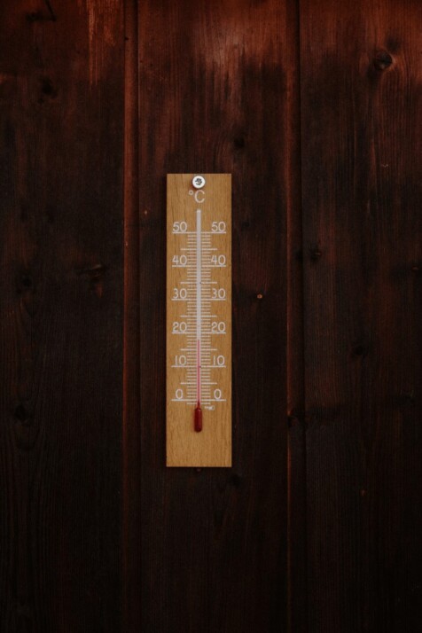 brown wooden thermometer in Celsius mounted to a wooden wall.