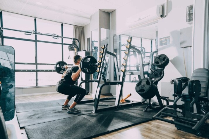 man in black track suit lifting weights in a gym.