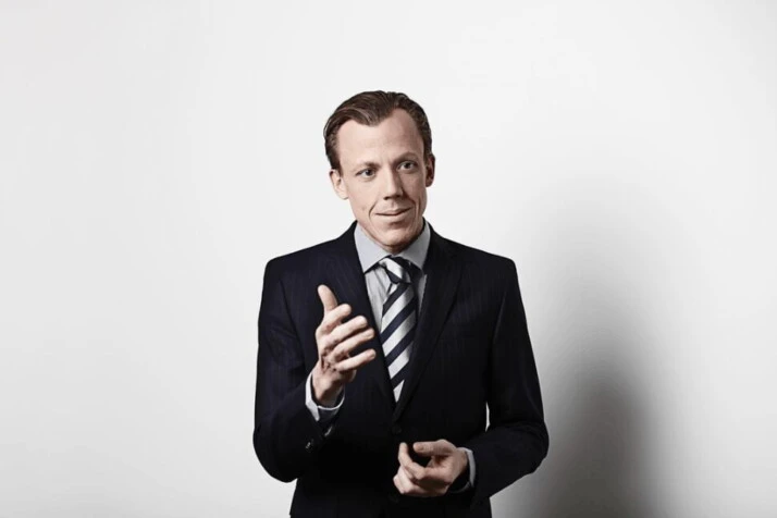 man in black suit jacket explaining something with a gesture