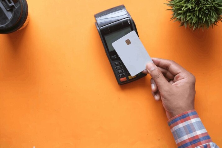 person holding black and white electronic device with white credit card