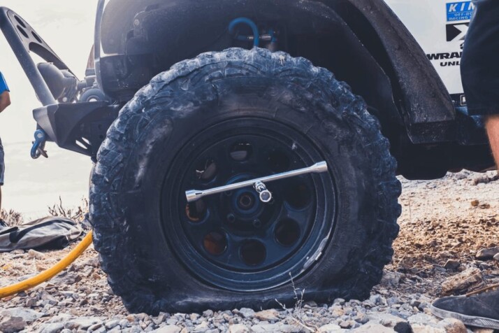 flat tire close-up photography on a jeep wrangler in the dirt sporting all terrain tires.