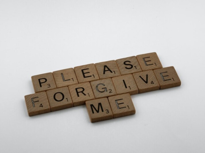 brown wooden blocks with 'please forgive me' inscription on white surface 