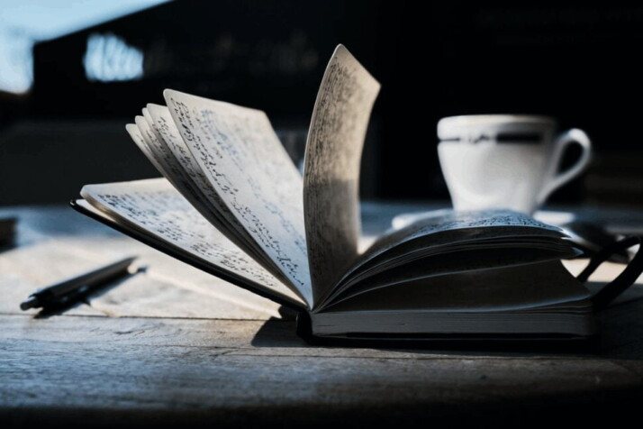 An open book placed on a brown wooden table.