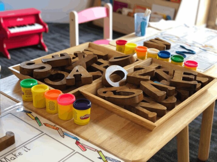brown wooden letters next to play dough in a kindergarten.