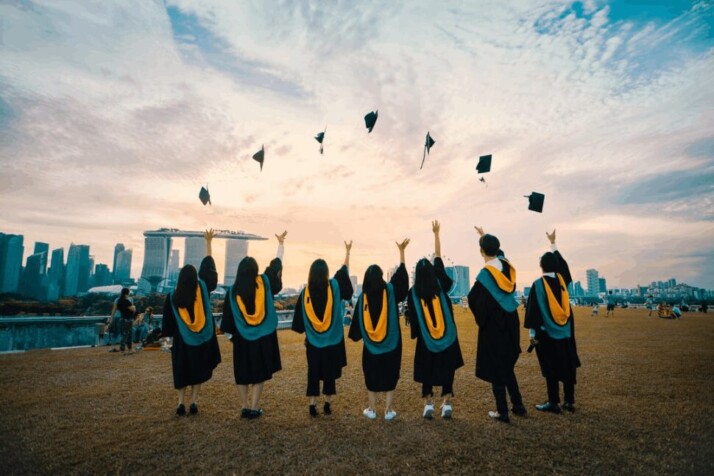 Students in convocation gown throwing hats in the air.