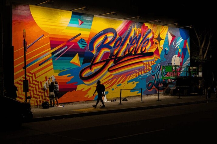 Believe mural painting in night time on a dimly lit street.