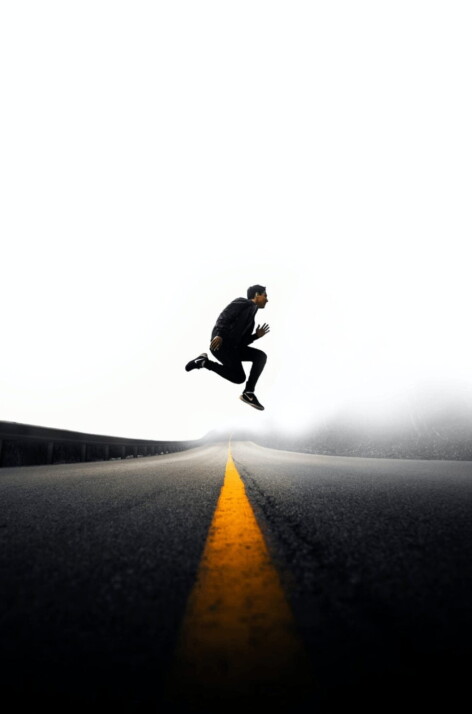 A man jumping above gray and yellow concrete road at daytime