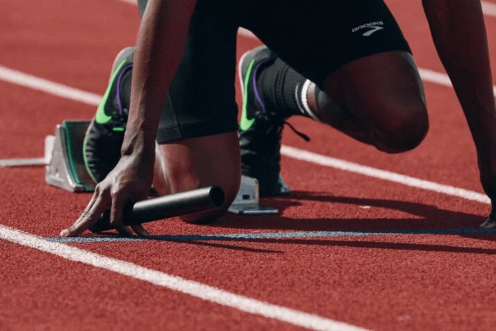 man preparing to start the race on a red clay track