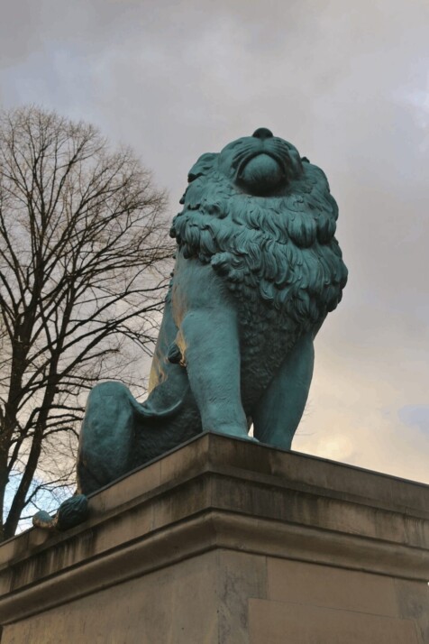 green statue of a lion holding his head high.