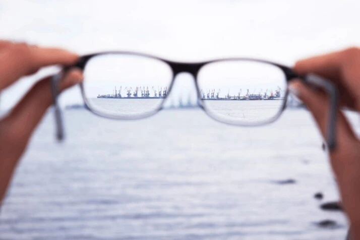 a nearsighted person holding eyeglasses to see a port.