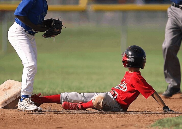 two boys playing baseball, one is wearing red and the other blue.