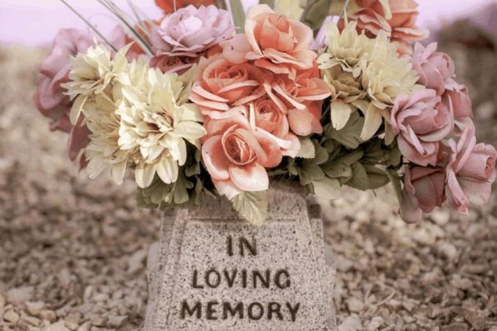 A pink and white flower bouquet on a gray concrete tomb.