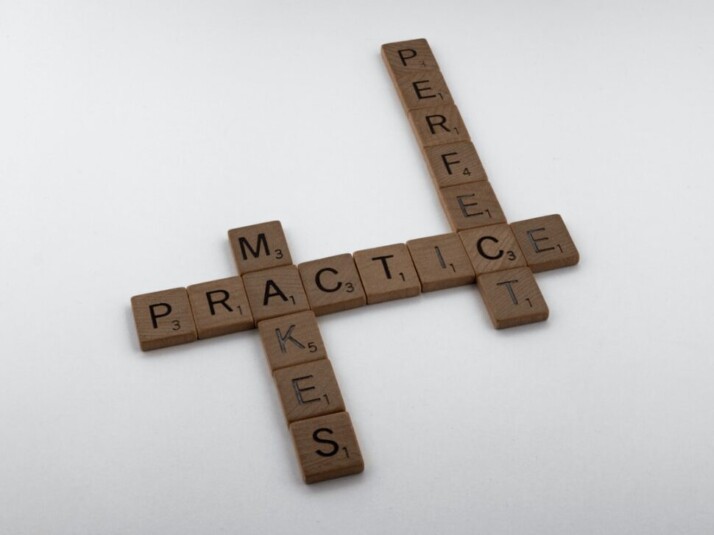 brown wooden Scrabble pieces that say Practice Makes Perfect on white surface
