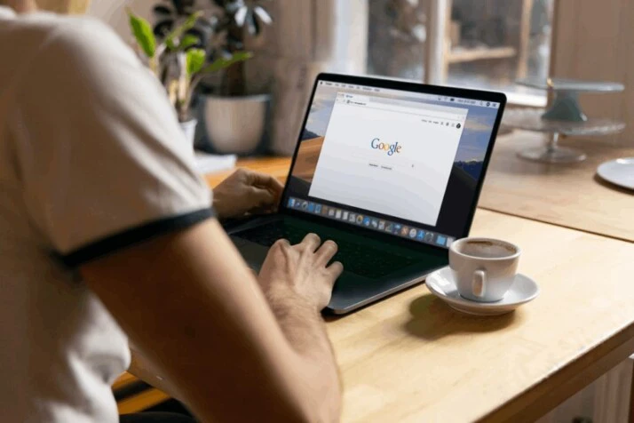 person using black laptop computer near mug on table