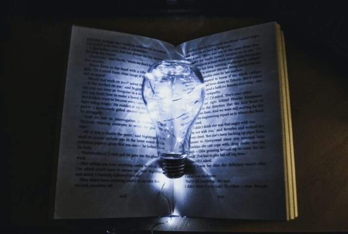 A lit bulb, nestled in a book, as if to represent an idea.