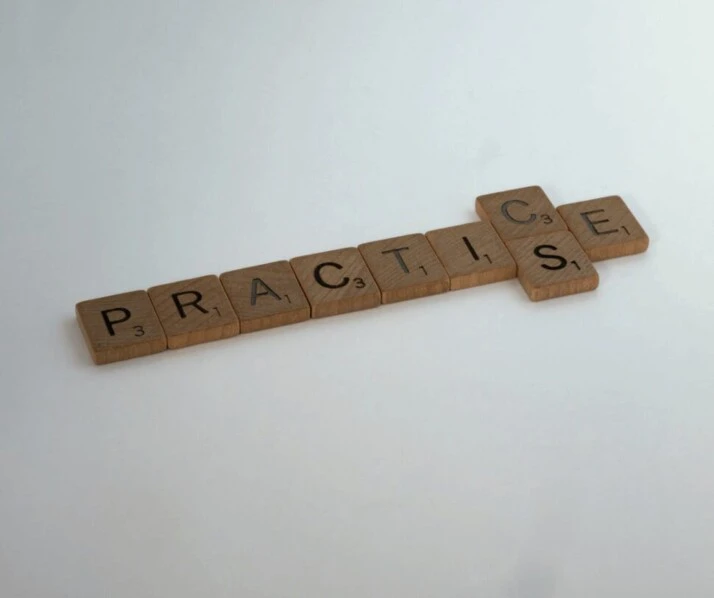PRACTICE brown wooden scrabble blocks on a white surface.