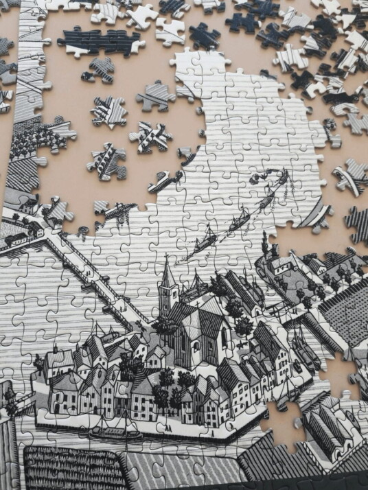 An unfinished puzzle of a town that is in black and white