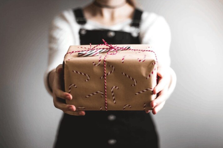A young lady handing you a wrapped gift box.