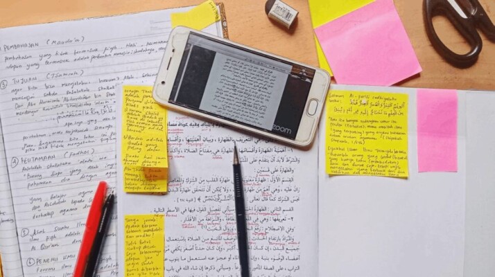 a white smartphone on top of notes that are written in Arabic.