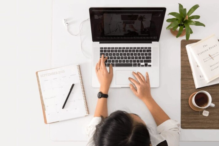 A person studying using a Macbook Pro and taking notes.