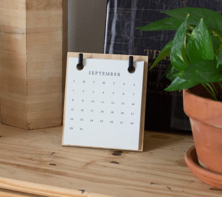 white braille paper on brown wooden table beside flower vase