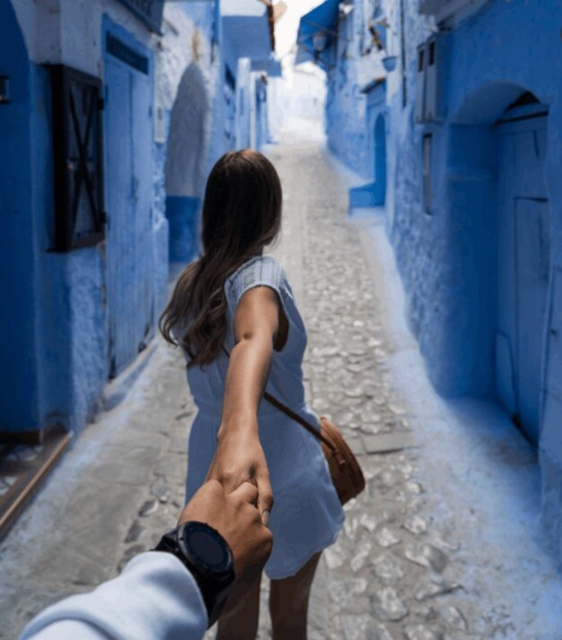 woman leading a man by holding his hand while walking on alley